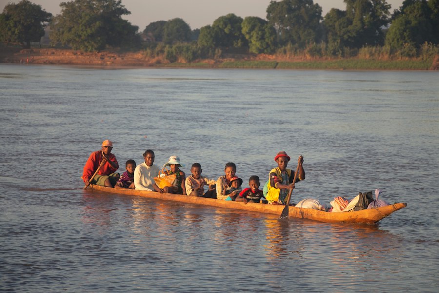 Dugout canoe laden with villagers gliding along a calm river in western Madagascar (the Tsiribihina) in the morning light