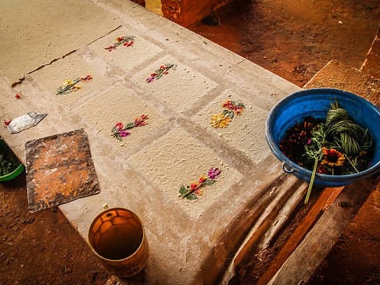 Antemoro paper decorated with flowers being made on a frame beside a basin of flowers, in Ambalavao.