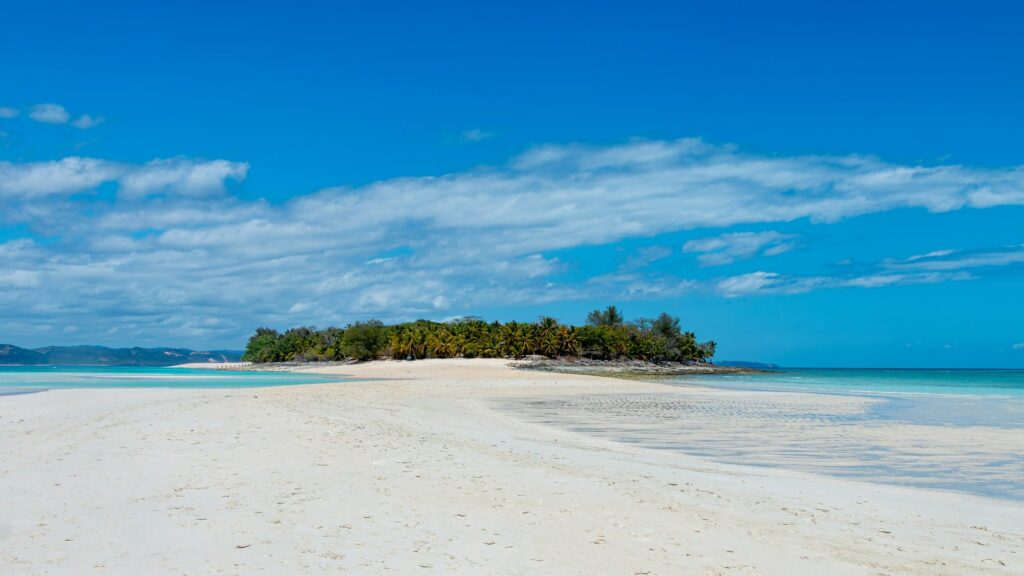 A white sandbank and an islet of coconut palms beside a turquoise lagoon in Madagascar