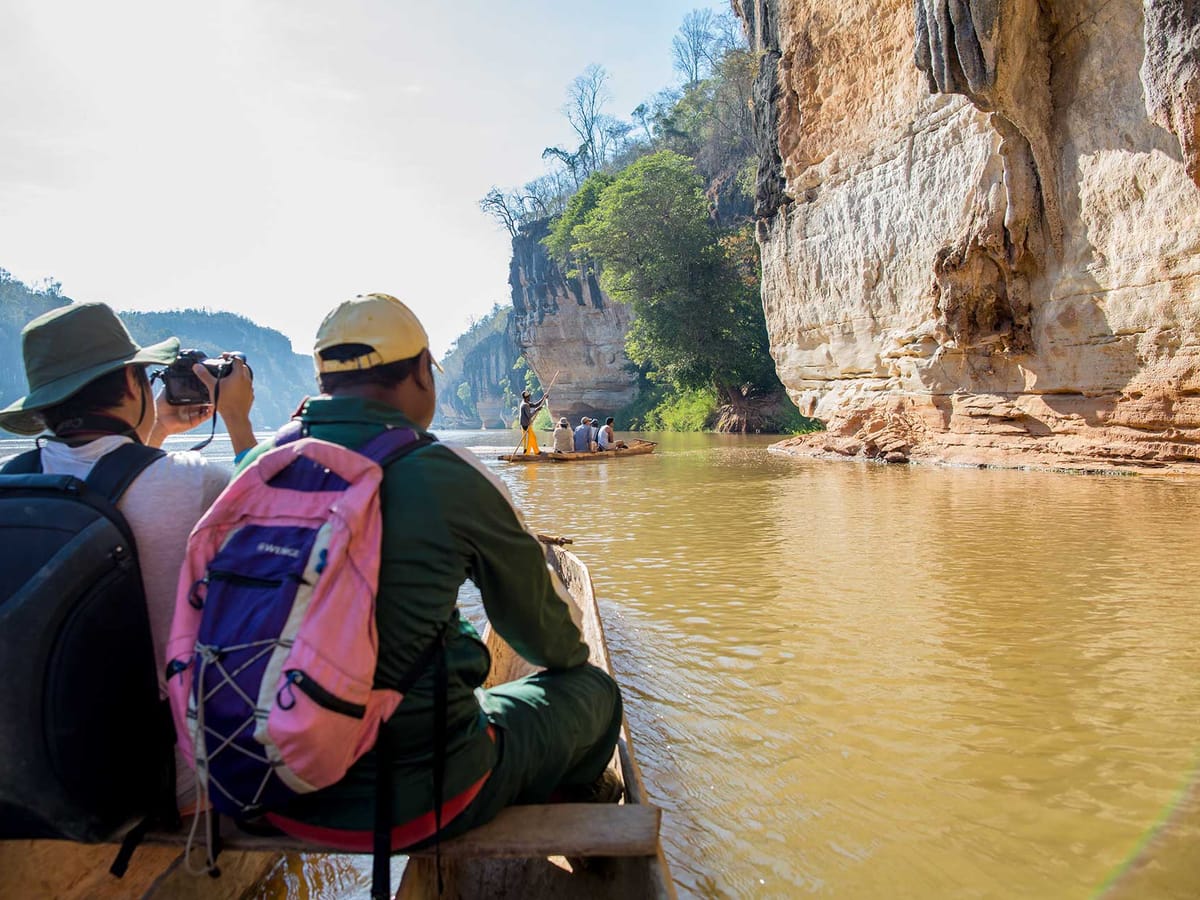 Two travellers in a dugout canoe on the Manambolo River facing the tall limestone cliffs of the gorge near Bekopaka.