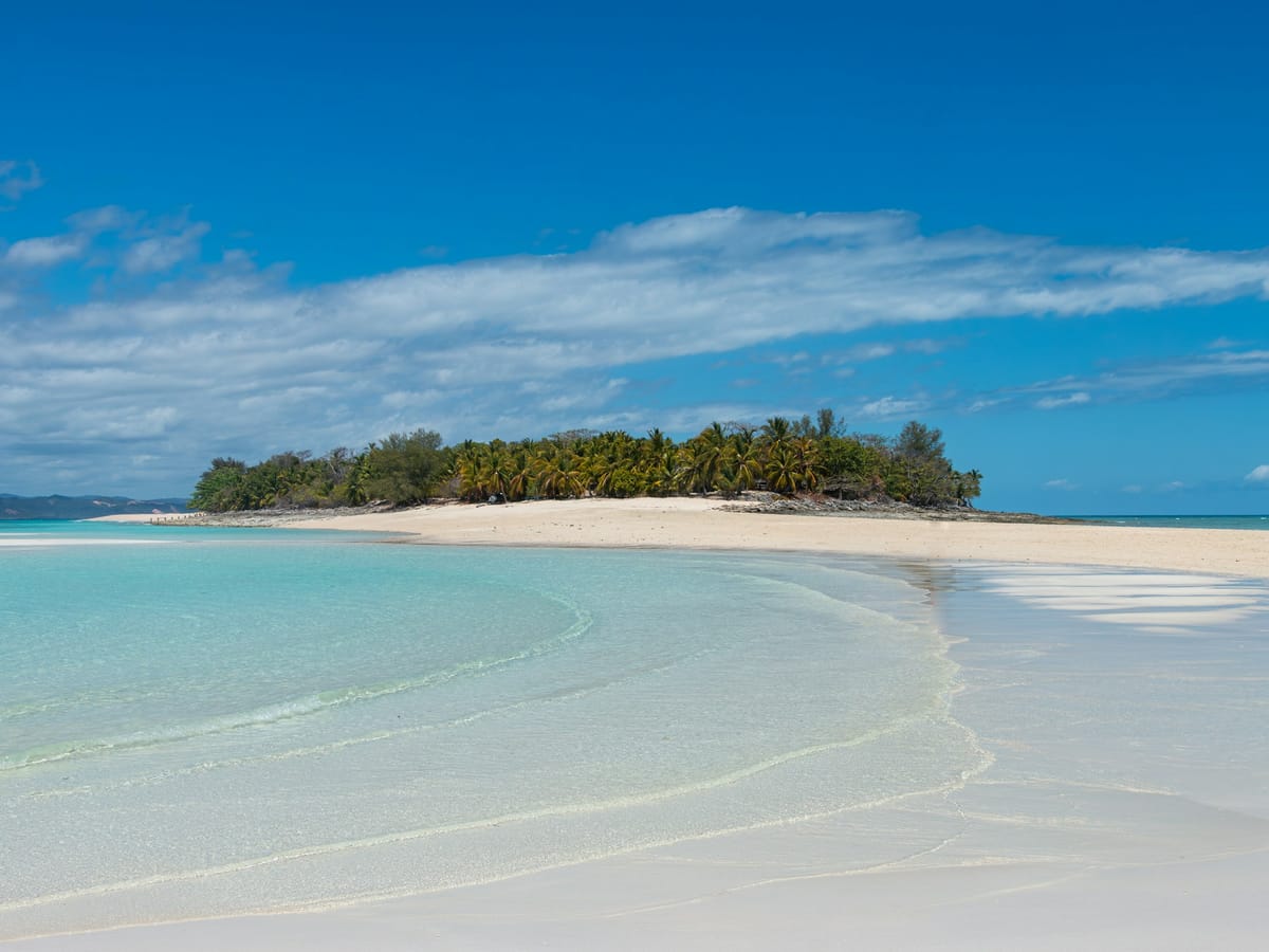 A white sandbar and shallow turquoise water below a palm-covered islet at Nosy Iranja, south-west of Nosy Be.