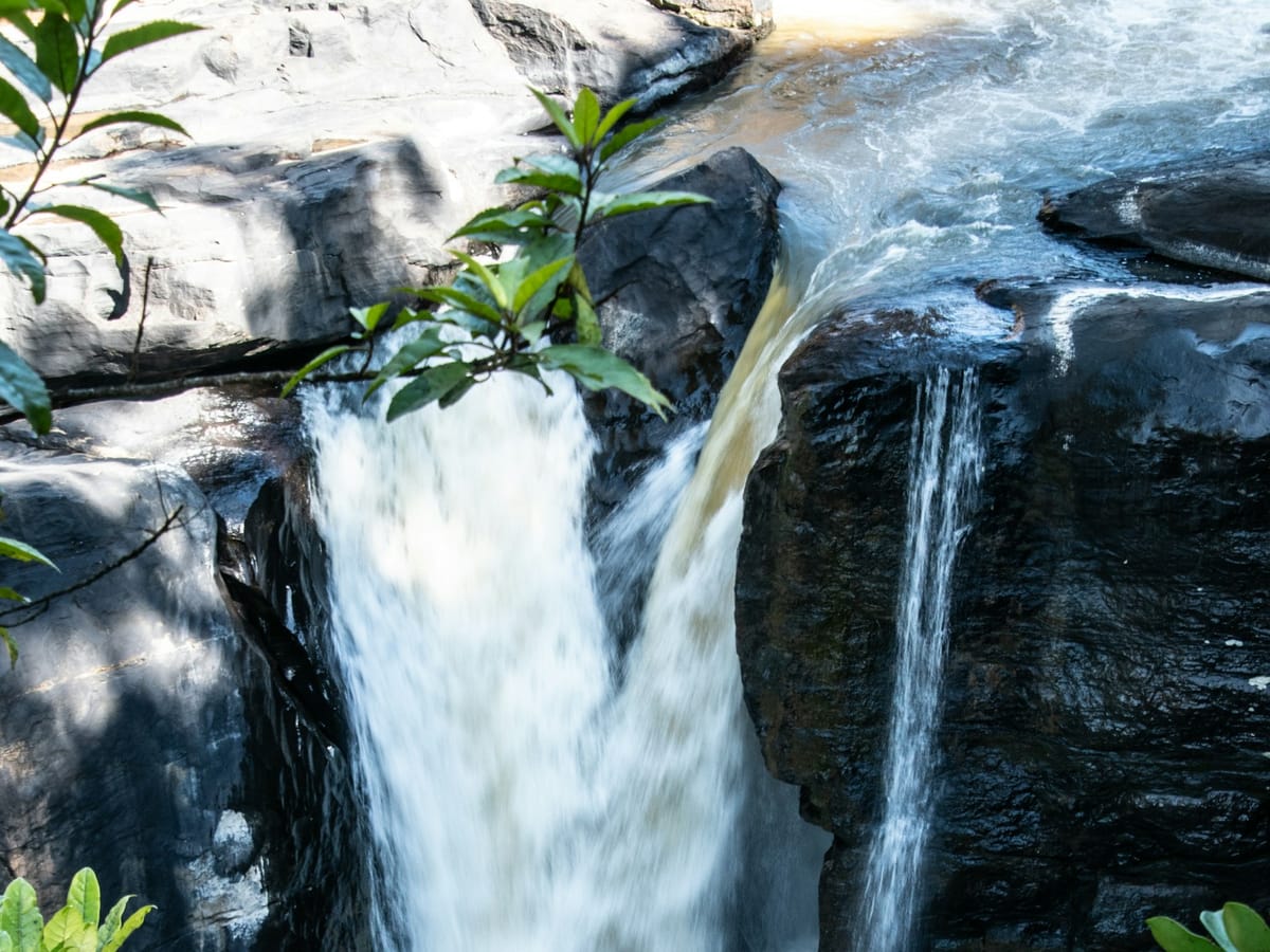 Waterfall pouring between dark rocks and green plants in Ranomafana National Park.