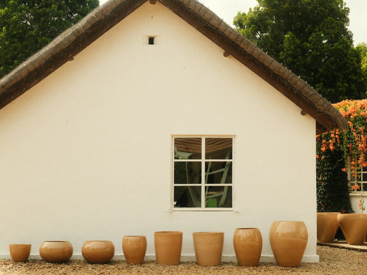 Terracotta pots of all sizes lined up along the wall of a white thatched house in Antsirabe.