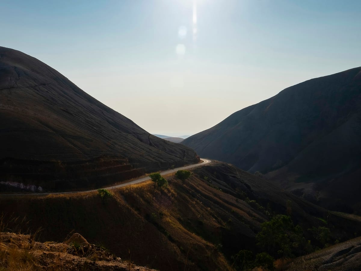 A paved road winding between bare hills, against the light, on the road to southern Madagascar.