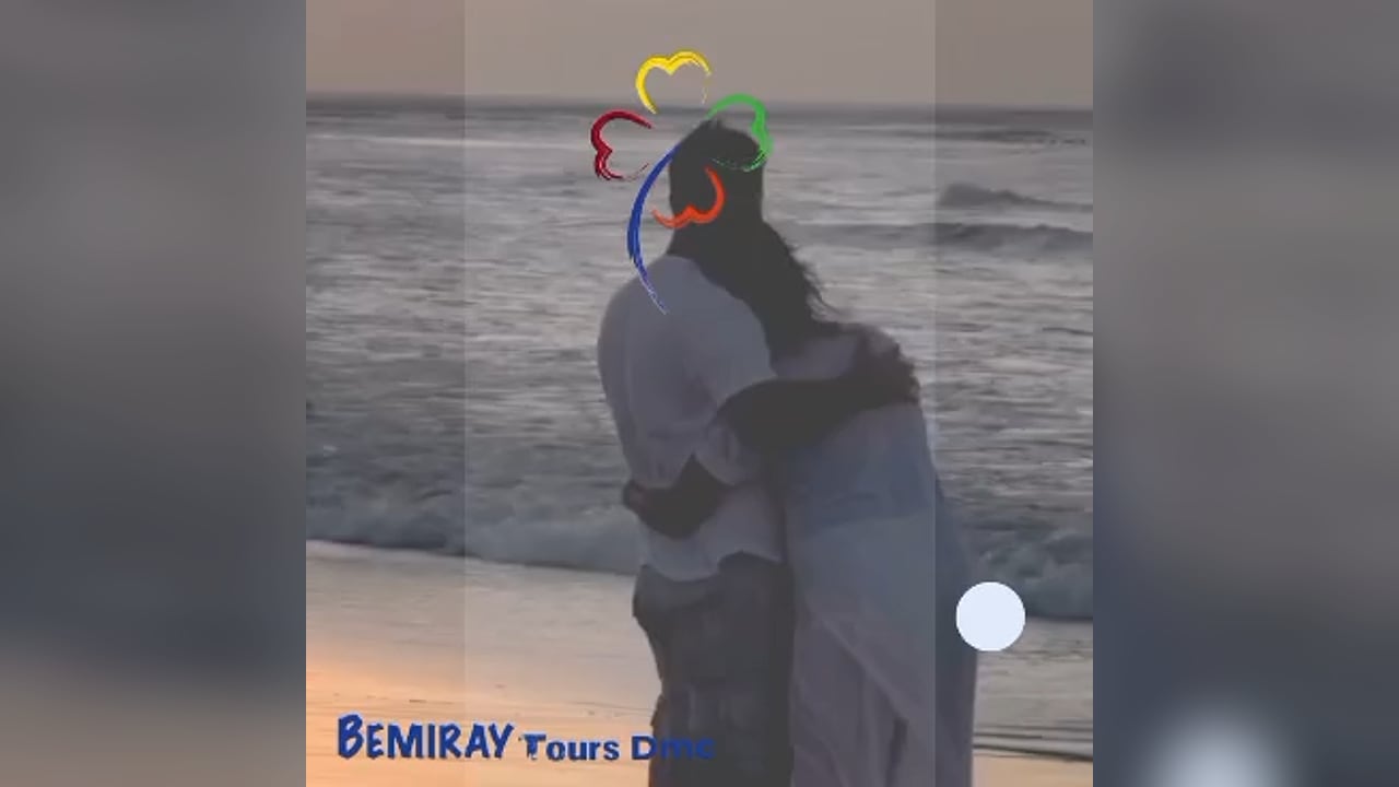 A couple embracing as they face the ocean at sunset